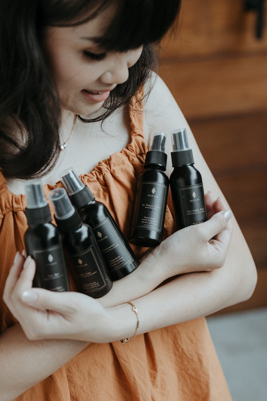 An armful of Ollie & Co. room spray bottles in black packaging